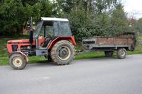 na poboczu drogi stoi ciągnik rolniczy z przyczepą