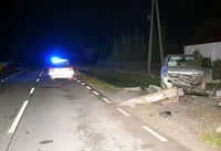 na ulicy stoi radiowóz, w przydrożnym rowie samochód marki Mitsubishi po uderzeniu w betonowy przepust