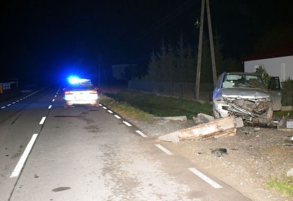 na ulicy stoi radiowóz, w przydrożnym rowie samochód marki Mitsubishi po uderzeniu w betonowy przepust