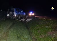 na ulicy stoi radiowóz, w przydrożnym rowie samochód marki Mitsubishi po uderzeniu w betonowy przepust