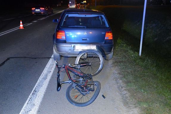 na jezdni stoi osobowy Volkswagen przed nim leży rower
