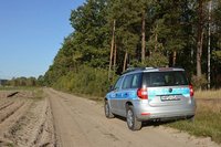 radiowóz na polnej drodze na skraju lasu