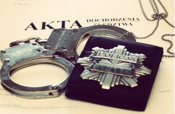 na aktach sprawy leżą kajdanki i policyjna odznaka