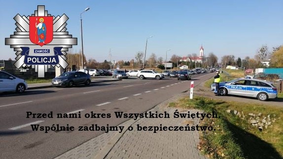 policjant obok radiowozu kontroluje bezpieczeństwo przy drodze zlokalizowanej obok cmentarza