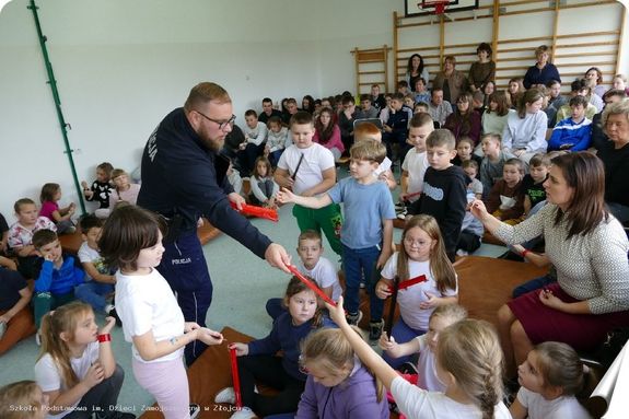 policjant rozdaje dzieciom odblaskowe opaski