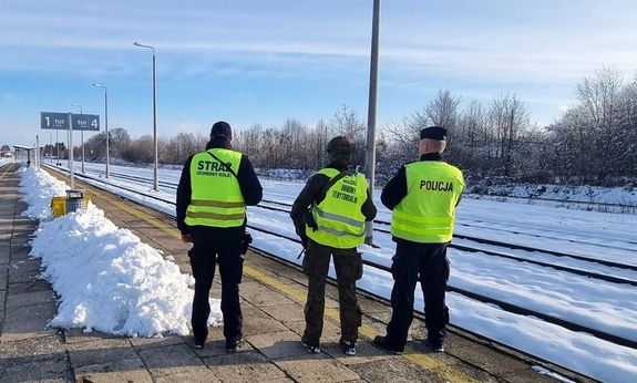 policjant funkcjonariusz Straży Ochrony Kolei oraz żołnierz w okolicach torowiska
