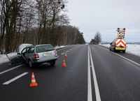 droga, na poboczu stoi rozbity osobowy volkswagen, na drugim pasie drogi stoi pojazd służby drogowej