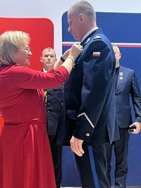 kobieta przypina policjantowi odznakę