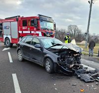 osobowe audi uszkodzone w wyniku zderzenia z innym pojazdem osobowym, za samochodem stoi policjant, a w tle wóz strażacki