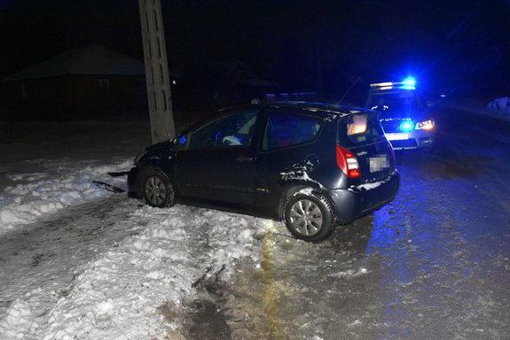 Osobowy citroen, którego kierująca uderzyła w słup energetyczny. Za osobówką na jezdni stoi radiowóz.