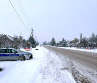 radiowóz stoi na ośnieżonym poboczu, zaśnieżona droga
