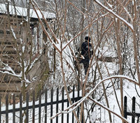policjant idący po śniegu w kierunku drewnianego budynku
