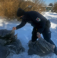 policjant ze sterty worków z węglem bierze dwa worki