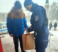 Policjant z patrolu przekazuje zakupy osobie bezdomnej