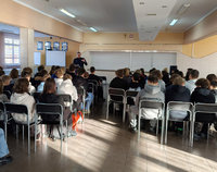 w czasie spotkania profilaktycznego policjant stoi przed młodzieżą siedząca na krzesłach