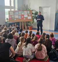 policjant podczas spotkania profilaktycznego rozmawia z uczniami