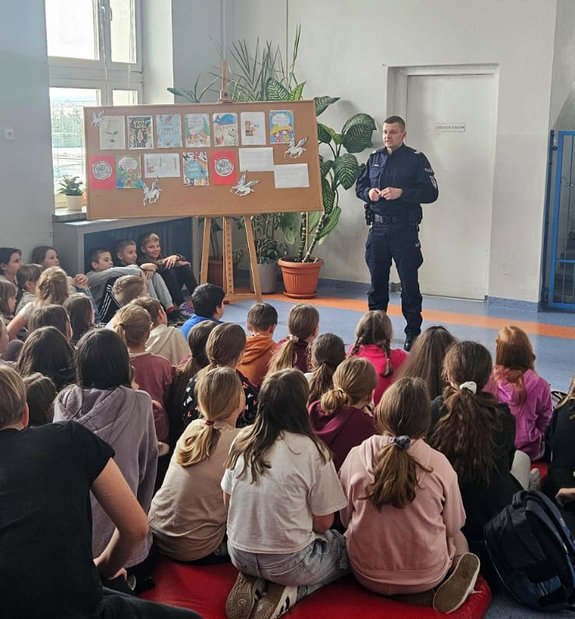 policjant podczas spotkania profilaktycznego rozmawia z uczniami
