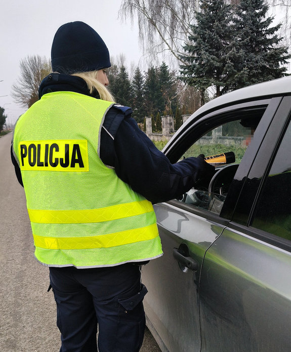 policjantka bada alkomatem stan trzeźwości kierującego samochodem