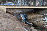 osobowe audi leży na boku w rzece, na moście stoi radiowóz