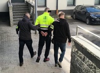 zatrzymany prowadzony przez dwóch policjantów kryminalnych