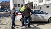 zatrzymany wsiada do samochodu w asyście dwóch policjantów kryminalnych