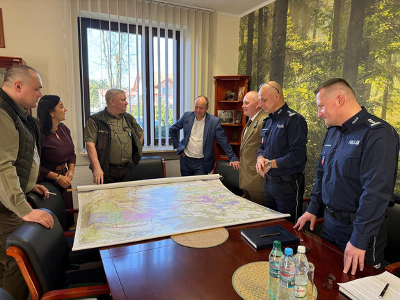 uczestnicy spotkania w Nadleśnictwie Zwierzyniec pochyleni nad stołem na którym rozłożona jest mapa