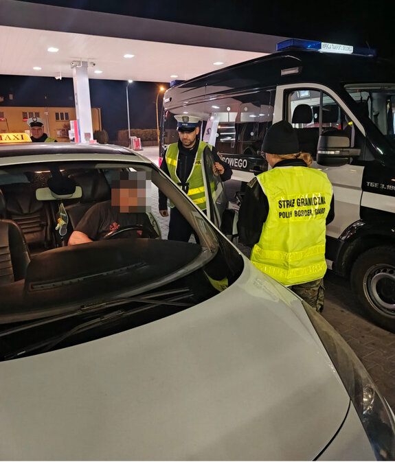 policjanci i funkcjonariuszka Straży Granicznej podczas kontroli kierującego taksówką