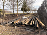 deski zniszczone przez pożar, za nimi opalone tuje