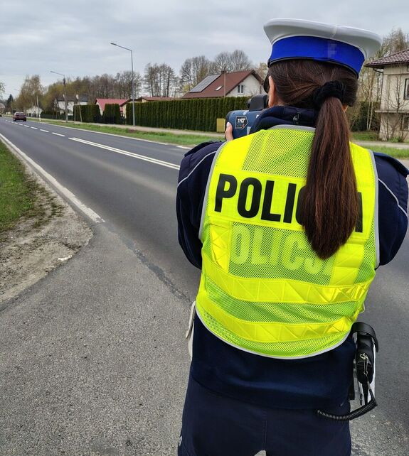 na poboczu drogi stoi policjantka z miernikiem prędkości