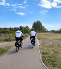 dwaj policjanci na rowerach służbowych jada ścieżką rowerową