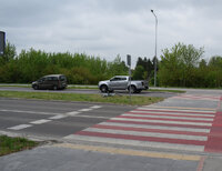 Jezdnia i przejazd dla rowerów na którym doszło do potracenia rowerzystki. Na pasie zieleni leży rower, za przejazdem stoi osobowy citroen i nieoznakowany radiowóz