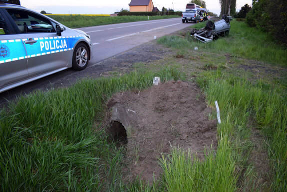 na poboczu stoi radiowóz, w rowie przy drodze na dachu leży osobowa toyota