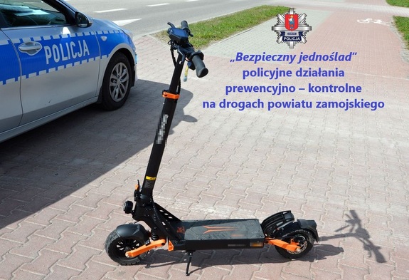 radiowóz a obok niego na chodniku stroi hulajnoga
