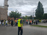 policjant stoi na drodze za nim idą uczestnicy marszu godności