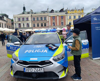 piknik z okazji Dnia Bezpieczeństwa Narodowego, policjantka obok radiowozu przy którym stoją również inne osoby