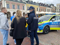 piknik z okazji Dnia Bezpieczeństwa Narodowego, policjantka obok radiowozu przy którym stoją również inne osoby