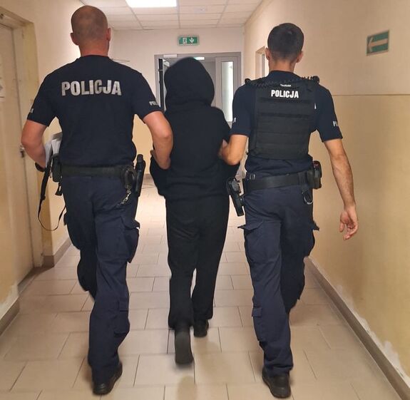 policjanci prowadzą zatrzymaną kobietę