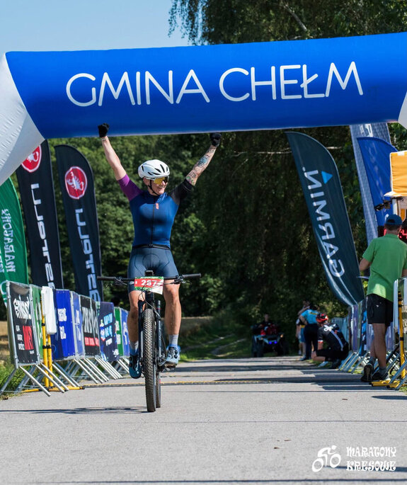 policjantka w stroju sportowym na rowerze przejeżdża metę wyścigu kolarskiego