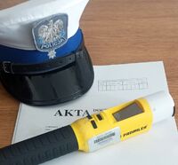 czapka policjantów ruchu drogowego leży na aktach postępowania przygotowawczego, obok leży tez alkomat