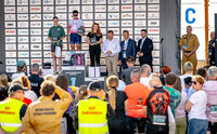 trzy kobiety na podium wyścigów kolarskich, pod sceną ludzie