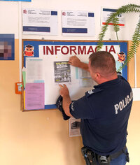 policjant n tablicy ogłoszeń przypina ogłoszenie