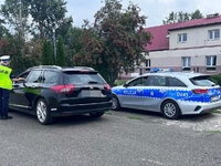 policjantka bada trzeźwość kierowcy pojazdu osobowego , za kontrolowanym pojazdem w zatoczce zaparkowany jest radiowóz