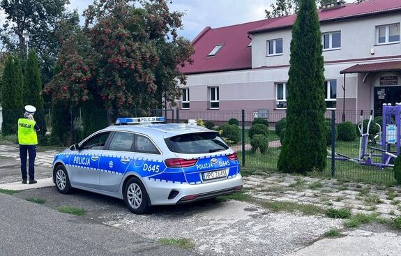 policjantka przy radiowozie zaparkowanym obok szkoły