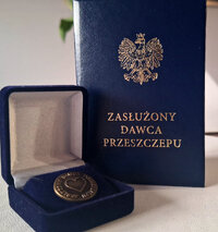 w pudełeczku odznaka, w tle okładki legitymacji z napisem Honorowy Dawca Przeszczepu