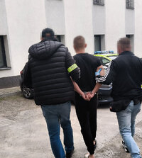 zatrzymany prowadzony w asyście dwóch policjantów