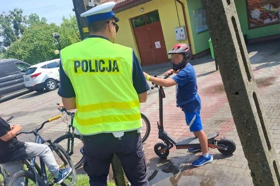 policjant kontrolujący dziecko, które jechało na hulajnodze elektrycznej