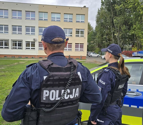 policjanci przed budynkiem szkoły w tle radiowóz