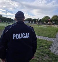 odwrócony plecami policjant przed boiskiem szkolnym