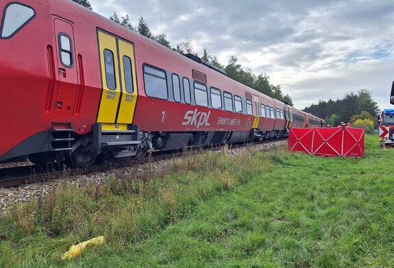 na torach stoi pociąg pasażerski , obok pociągu parawan