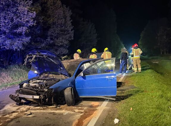 uszkodzone po dachowaniu osobowe Audi, w tle strażacy